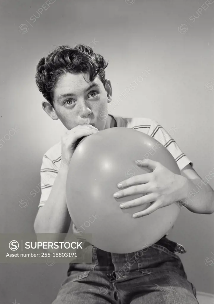 Vintage photograph. Boy blowing up balloon