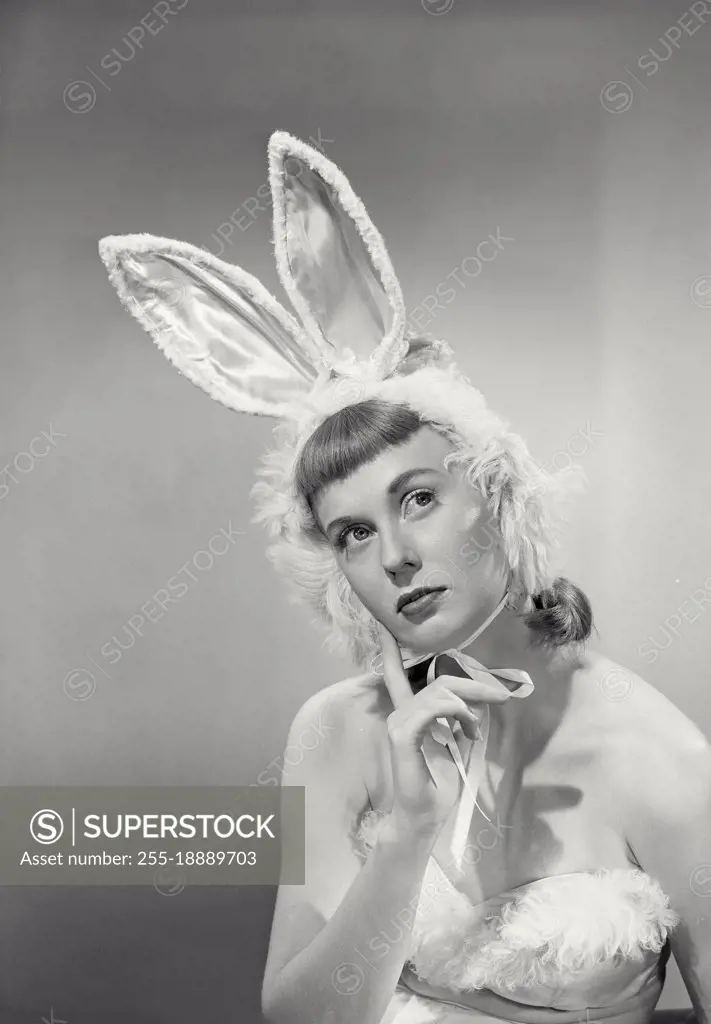 Vintage photograph. young woman wearing bunny ears with finger on chin