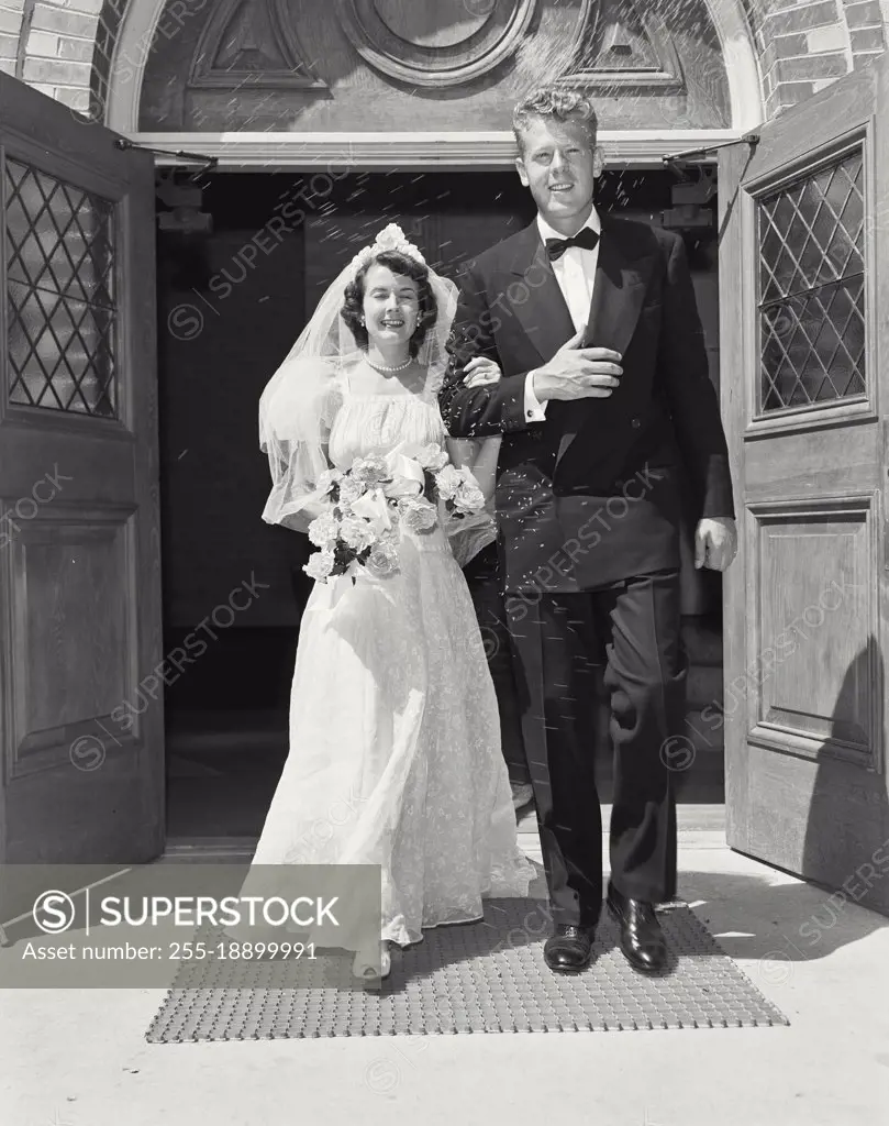 Vintage photograph. Bride and groom in front of church with rice being thrown in air