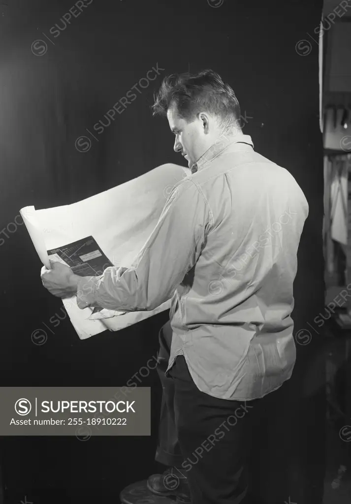 Vintage photograph. Man looking at blueprint