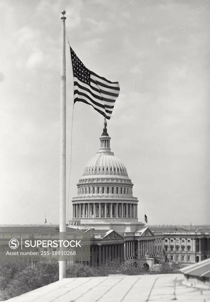 Vintage photograph. View of Capitol Building Rotunda in Washington DC with American Flag on pole in foreground