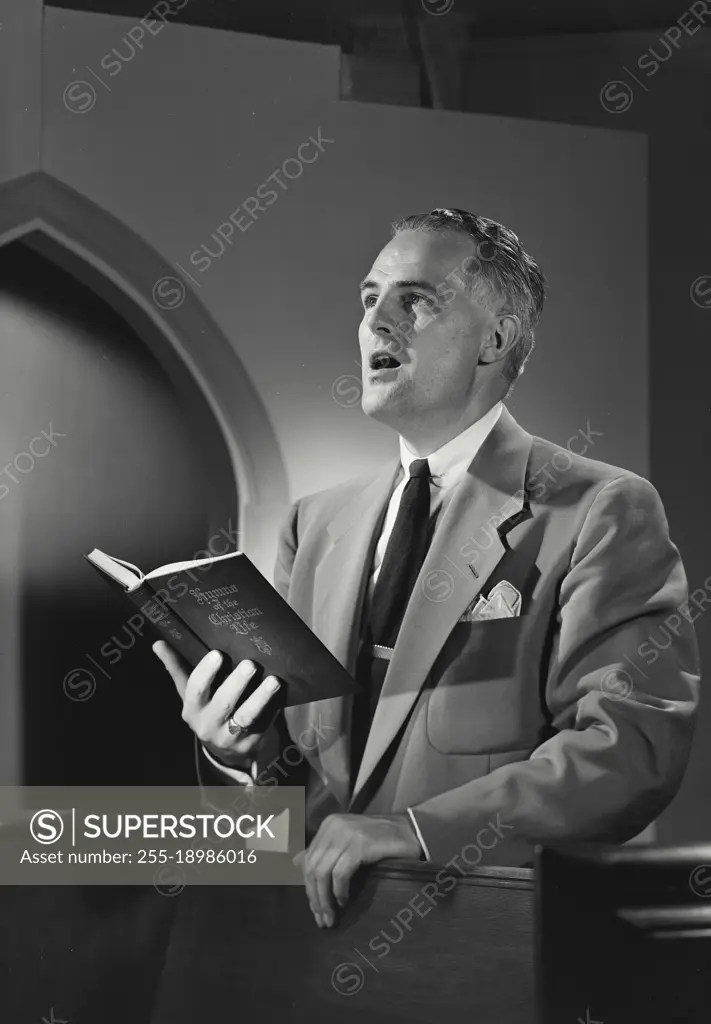 Vintage photograph. Man in church singing from Hymnal book