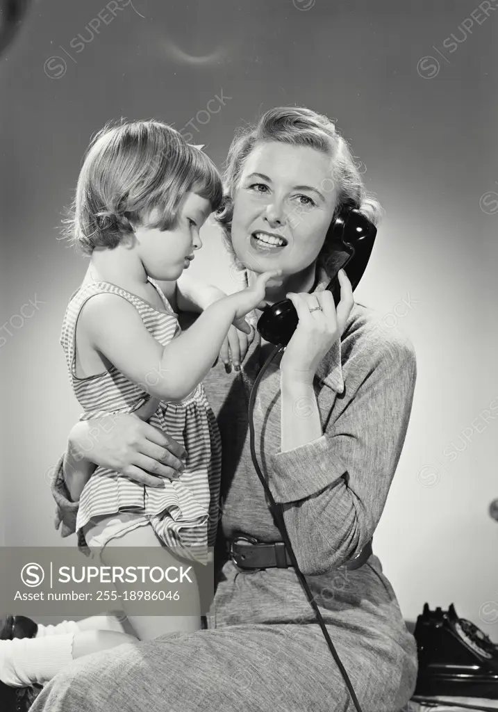 Vintage photograph. Daughter plays with mouthpiece while mother talks on phone