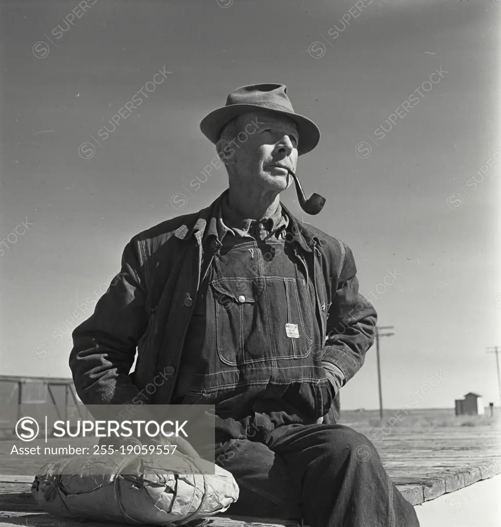 Vintage photograph. Portrait of farmer wearing overalls smoking pipe