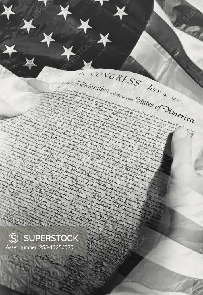 Photo illustration of hands holding Declaration of Independence in front of American flag