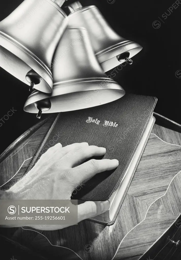 Photo illustration showing hand on Holy Bible with ringing bells in top corner