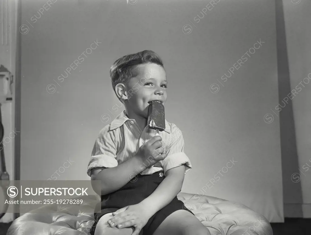 Vintage photograph. Little boy biting ice cream pop.