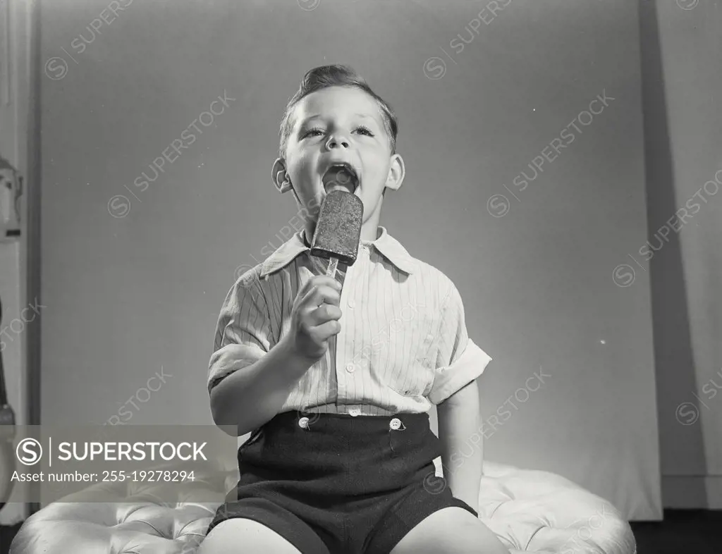 Vintage photograph. Little boy licking ice cream pop.