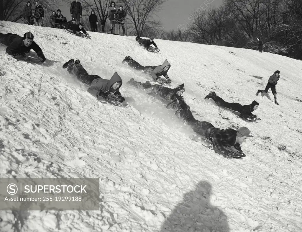 Vintage photograph. Children sledding down snowy hill