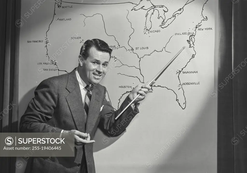 Vintage photograph. Man in suit and tie pointing at map