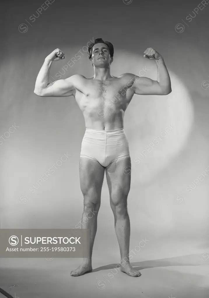 Vintage photograph. Bodybuilder flexing biceps.