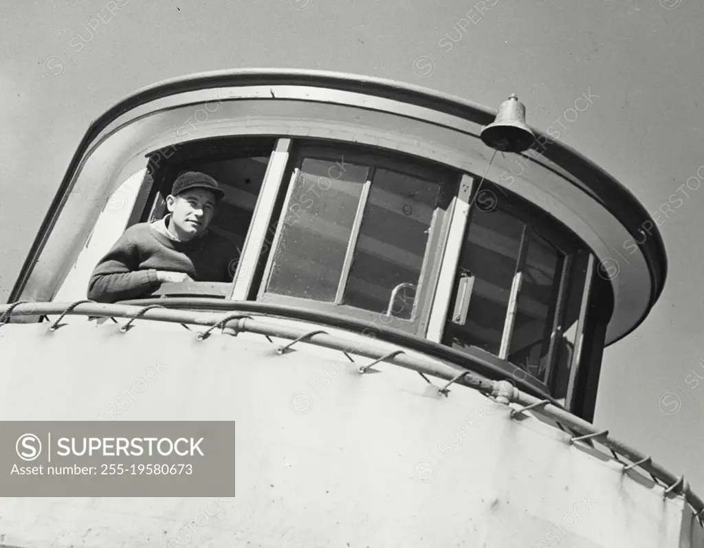 Vintage photograph. Lookout watching the slow steady progress of the boat as it heads out for the oyster grounds in the shallow waters of Gardner's Bay. Bluepoint Company