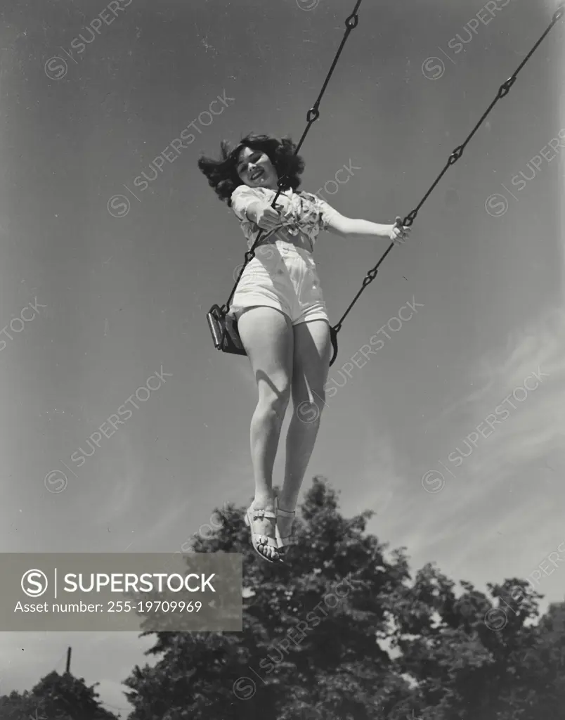 Vintage photograph. Looking up at young woman on swing