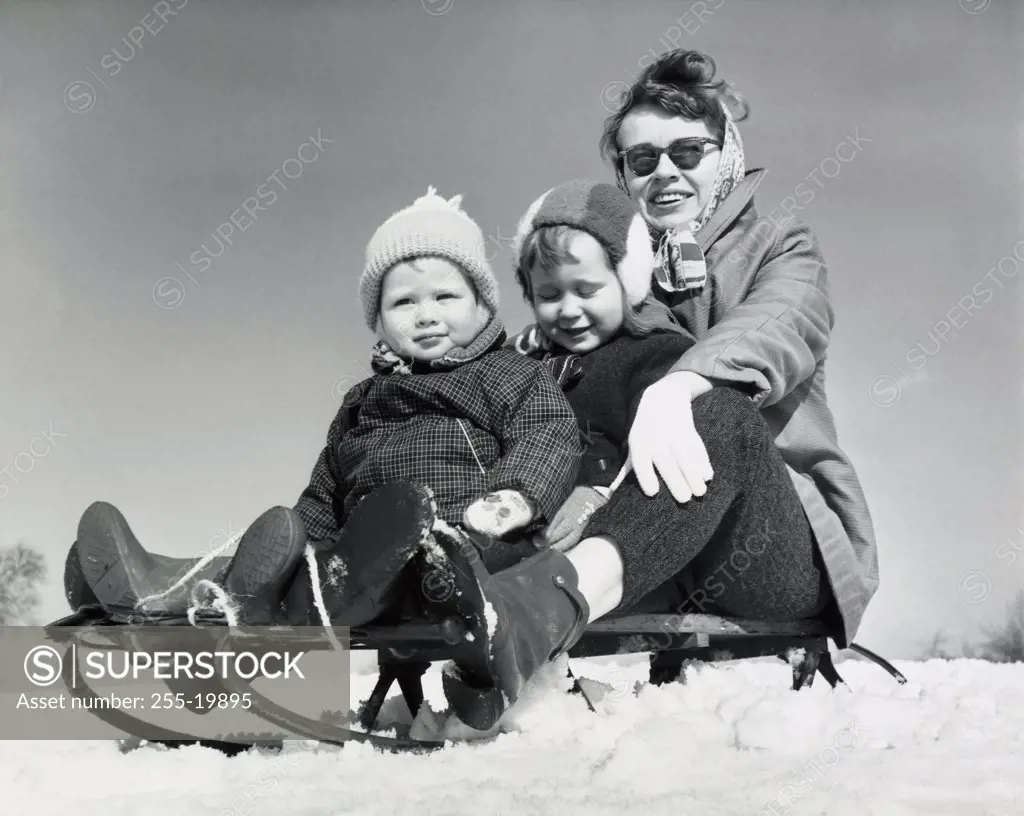 Close-up of a mother with her two children sitting on a sled