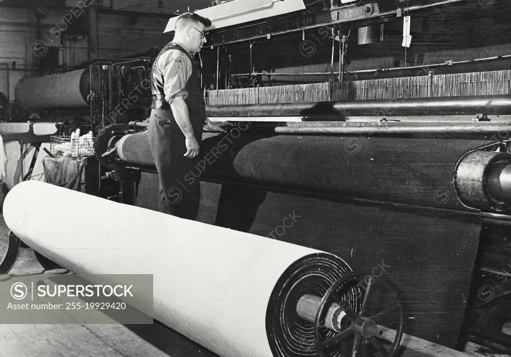 Setting the frame for an Axminster carpet. From the squared design on the roller, the colored yarns are wound onto spools ready for the loom.