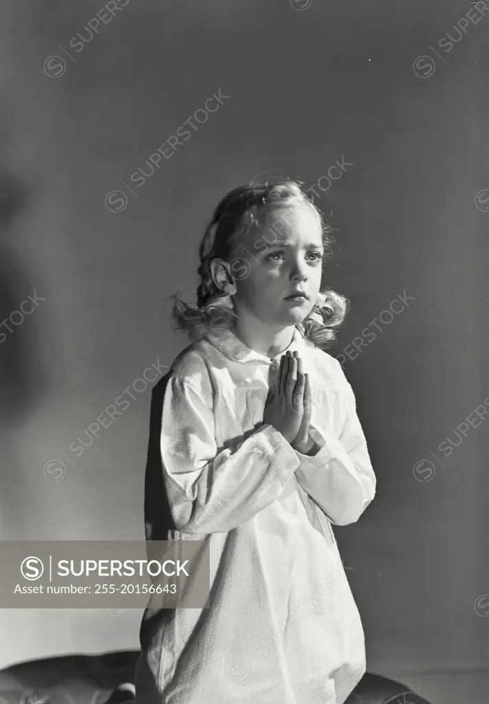 Vintage photograph. Young girl with blonde hair kneeling and praying