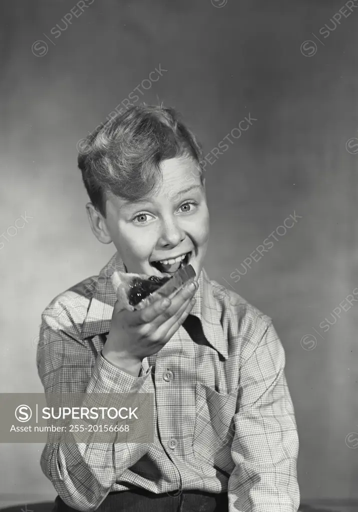 Vintage photograph. Young boy smiling eating toast