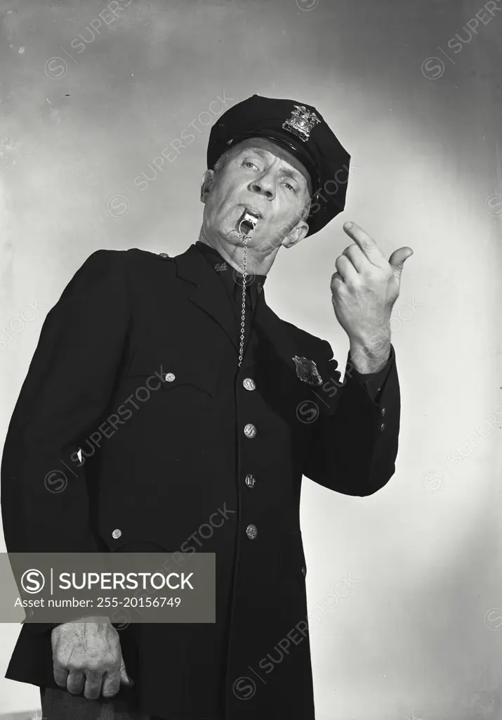 Vintage photograph. Man in police uniform with whistle in mouth making hand gesture