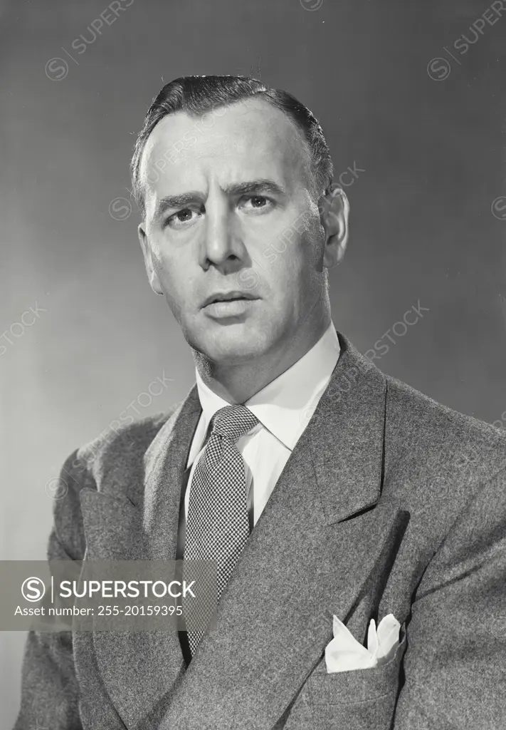 Vintage photograph. Dark Haired Businessman wearing suit and pocket square looking serious