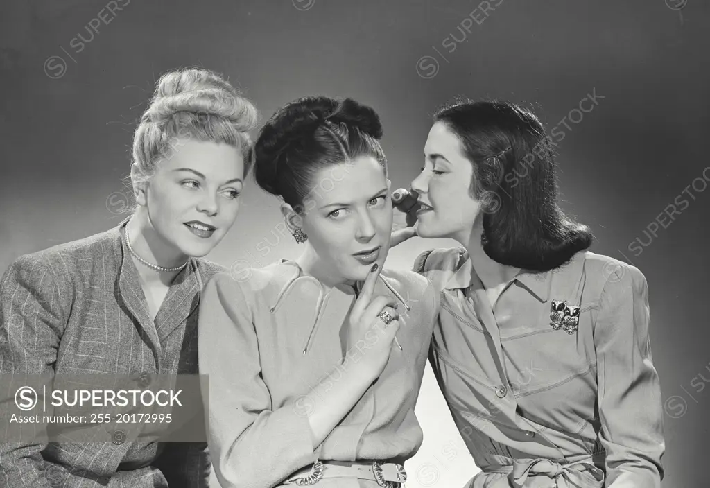 Vintage photograph. Three women wearing office attire telling secrets