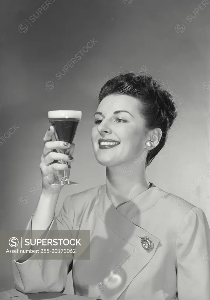 Vintage photograph. Woman staring at beer glass and smiling