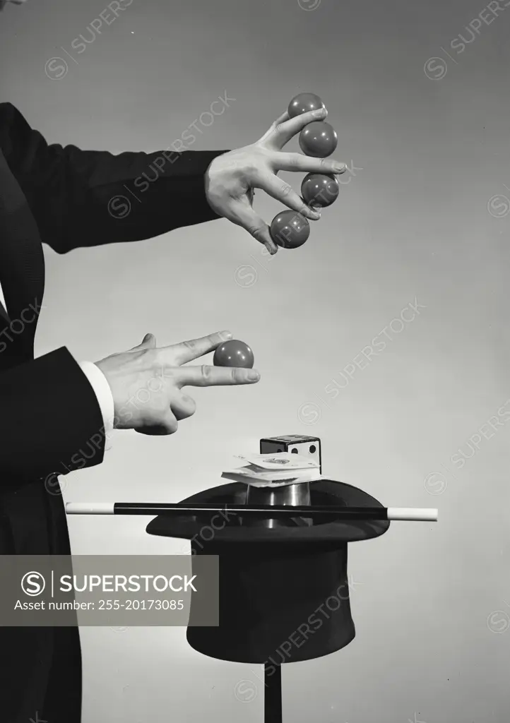 Vintage photograph. Magician holding up five balls in between fingers