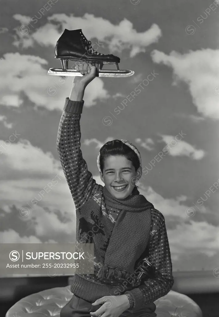 Boy in sweater holding up an ice skate