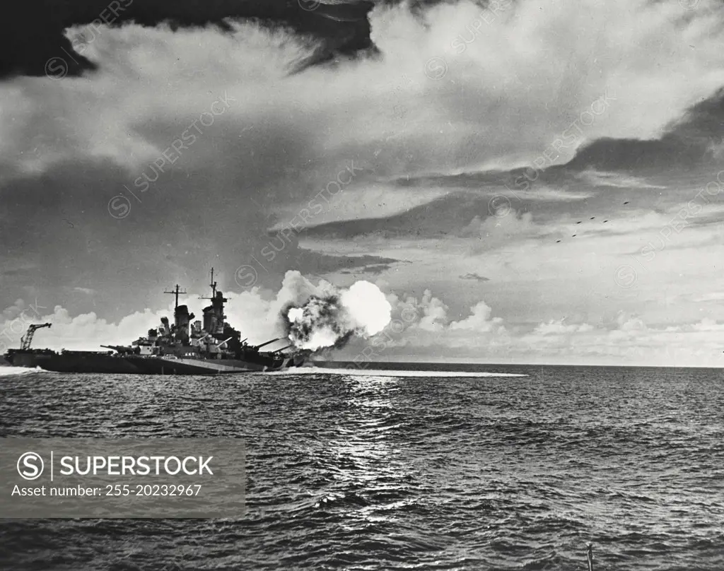 USS Missouri is shown as the 16 inch guns of her two forward turrets fire in salvo