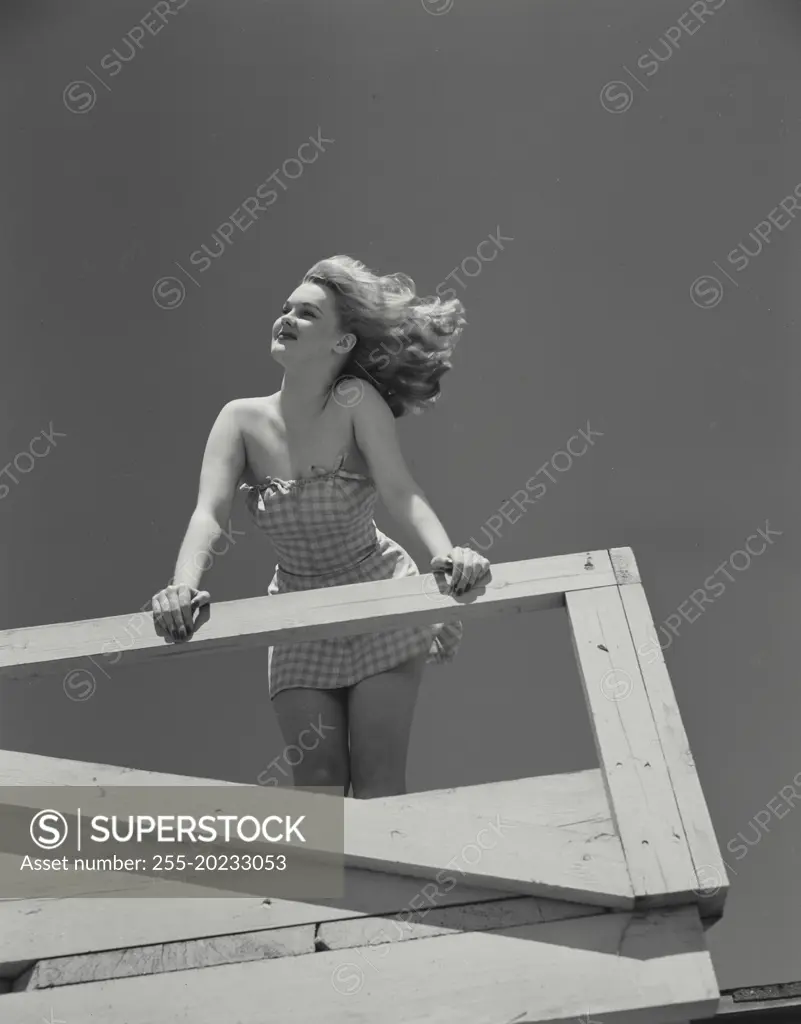 Woman in short dress leaning over railing of deck