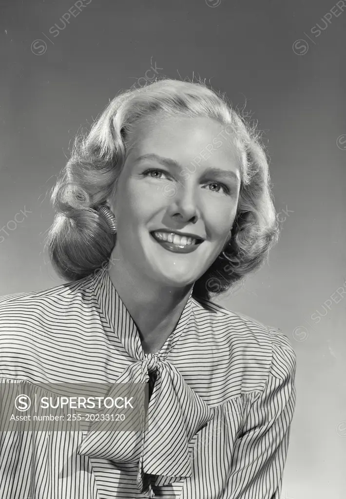 Woman in striped blouse with bow smiling at camera.