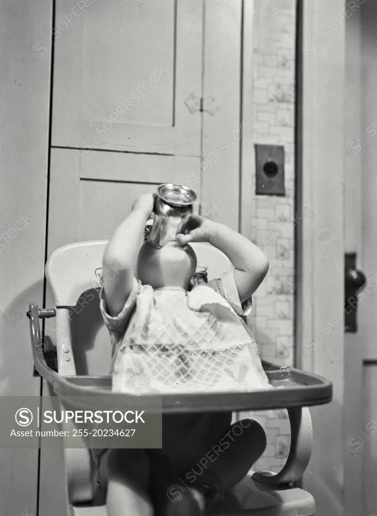 Baby girl in high chair drinking from cup