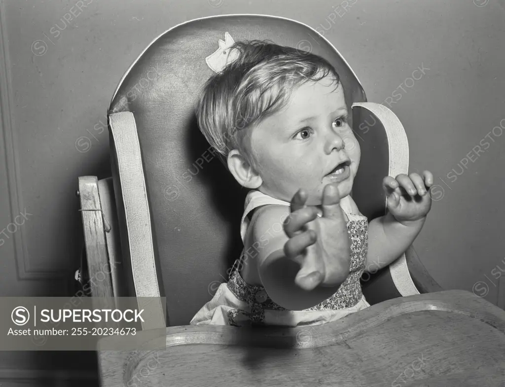 Baby in high chair reaching toward camera