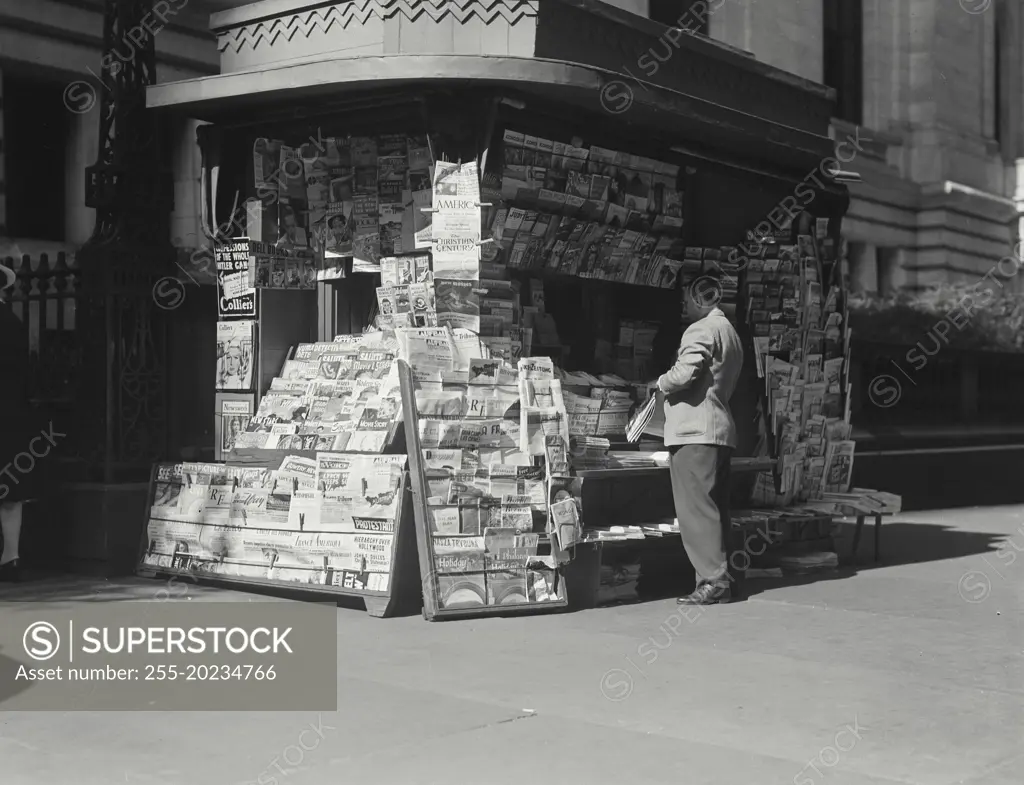 Man standing at news stand in town