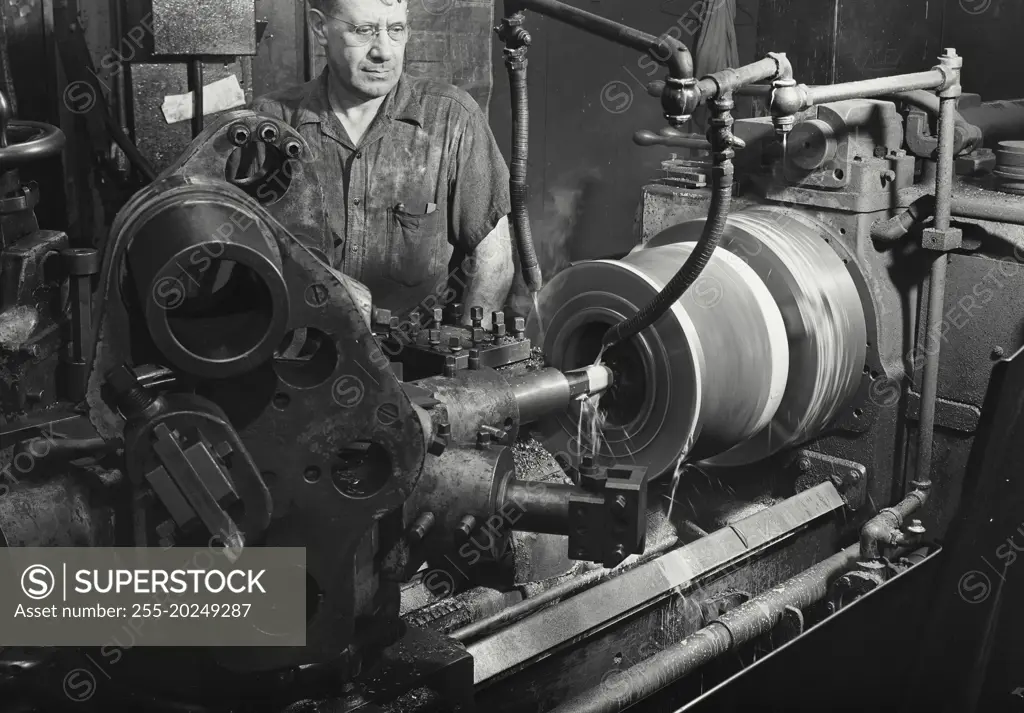 Worker standing behind multiple tooling machine in operation, Worthington Pump and Machinery Corporation, Harrison, New Jersey