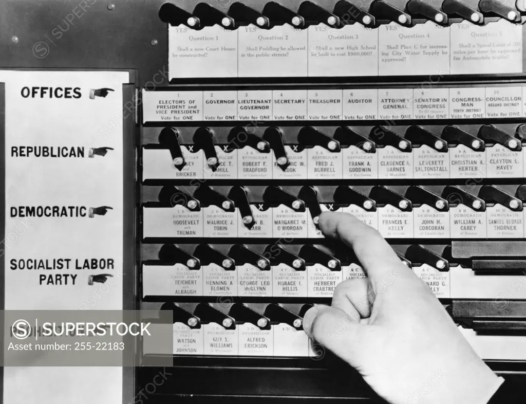 Close-up of a person's hand pushing lever of a voting machine