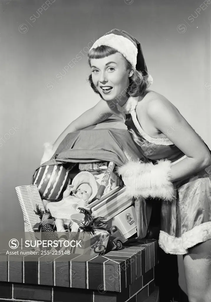 Vintage photograph. Portrait of a young woman dressed as santa dumping toys down chimney