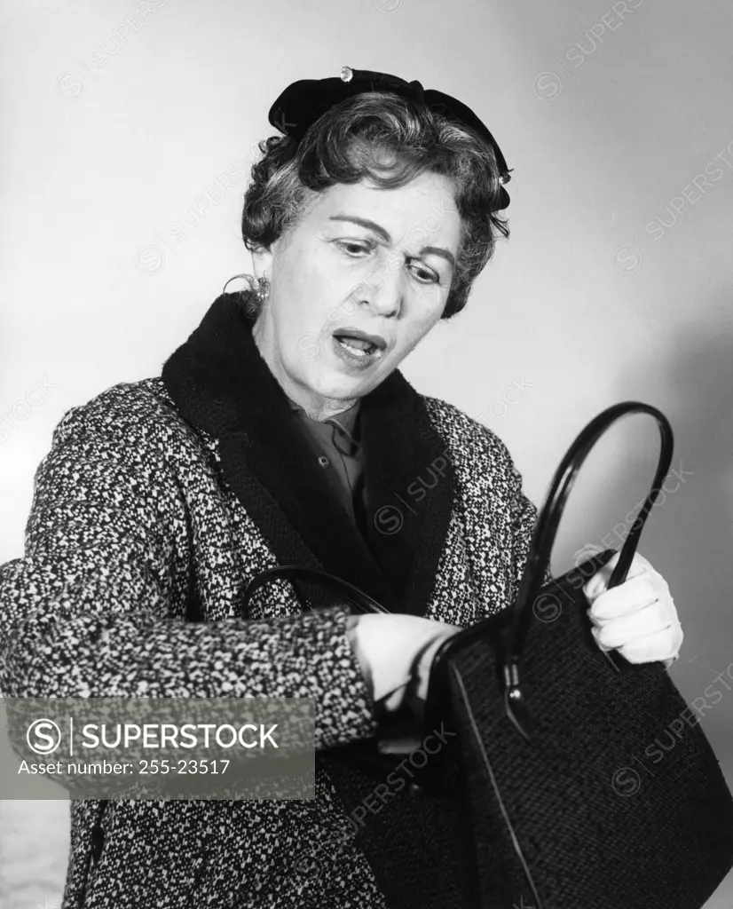 Surprised mature woman searching handbag