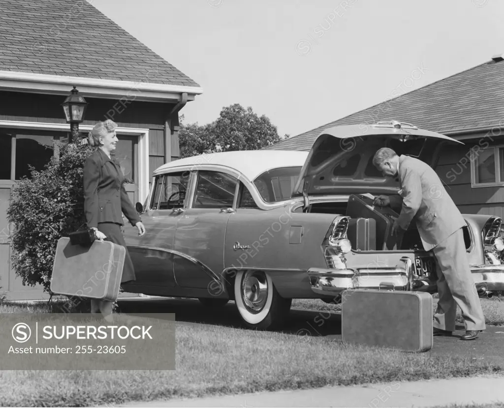 Senior couple loading luggage into car trunk