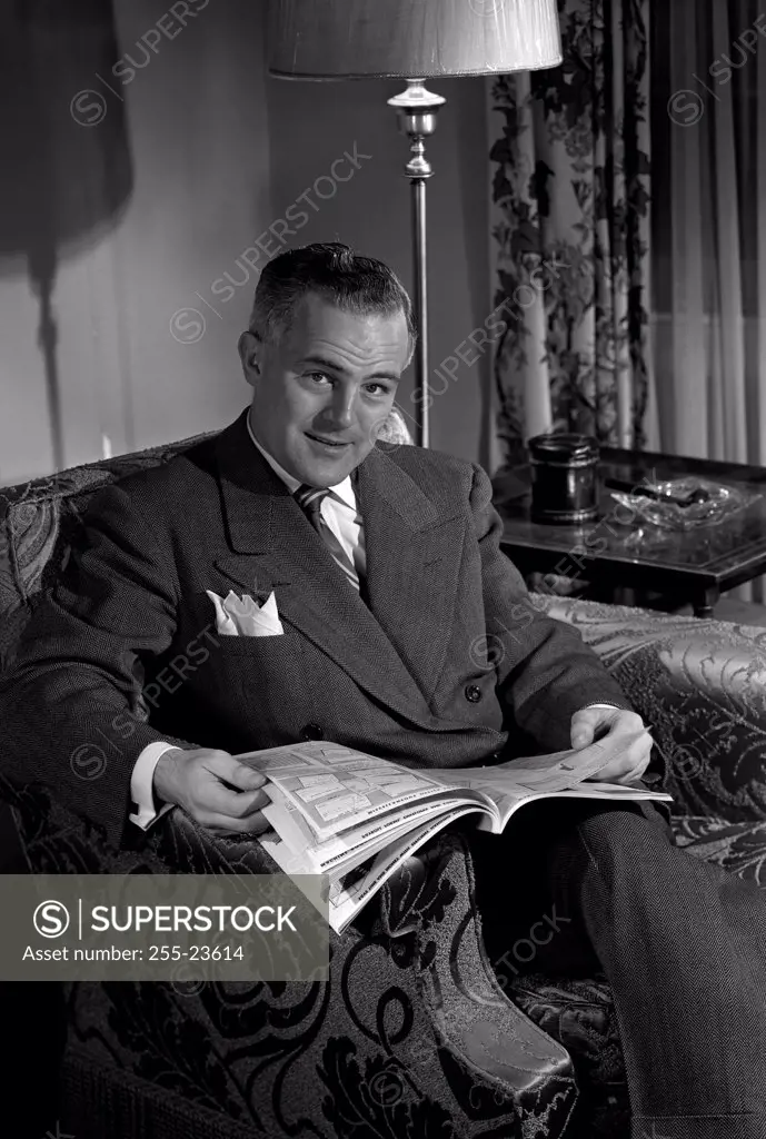 Portrait of mature man sitting in armchair, browsing comic