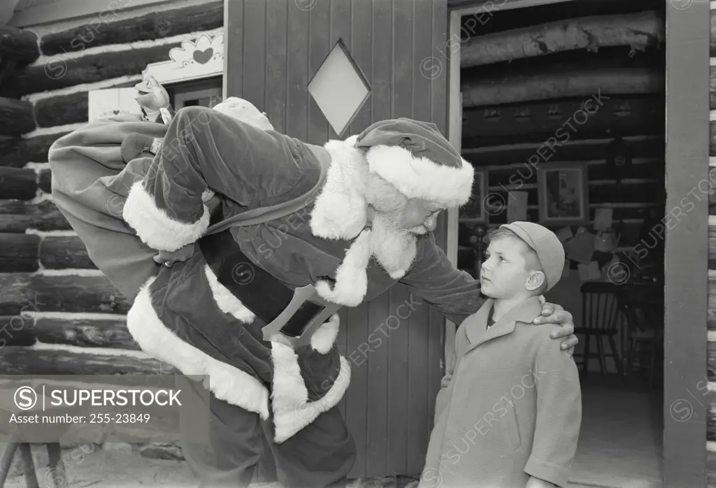 Vintage Photograph. Side profile of Santa Claus talking with boy