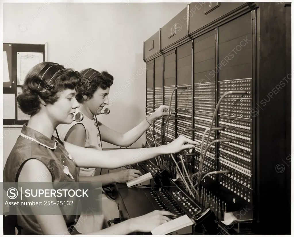 Side profile of two female telephone operators operating a switchboard