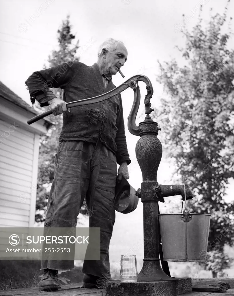 USA, New Hampshire, Lyme, senior man pumping water in garden