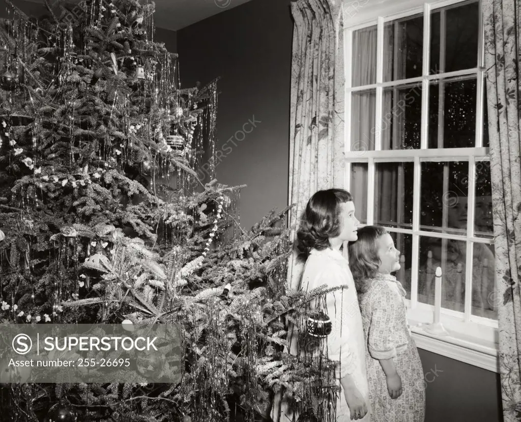 Side profile of two girls looking through a window