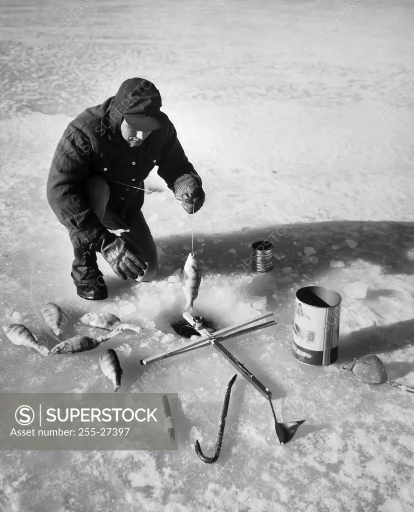 High angle view of a mid adult man fishing on ice