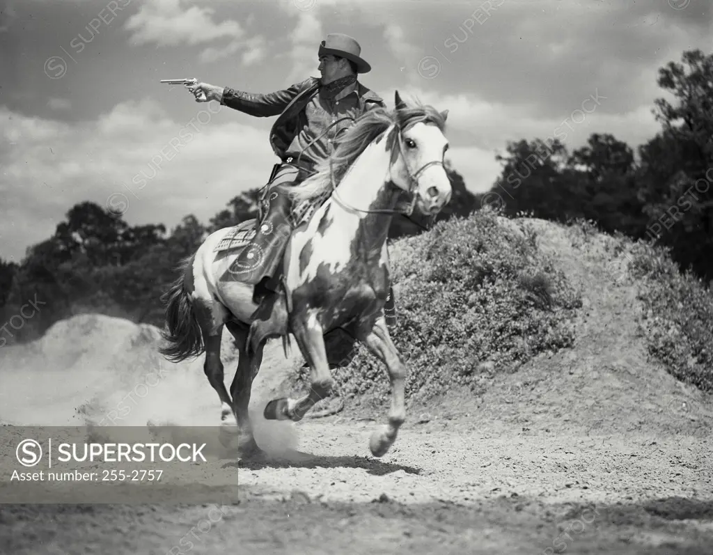 Vintage Photograph. Man in chaps riding on horses back shooting gun. Frame 1