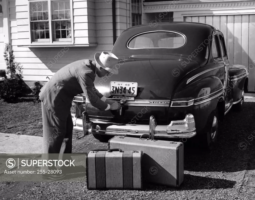 Man loading luggage into car trunk