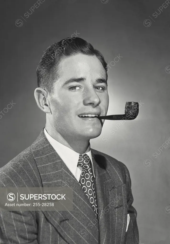 Young businessman wearing pinstriped suit and tie holding wooden pipe in mouth