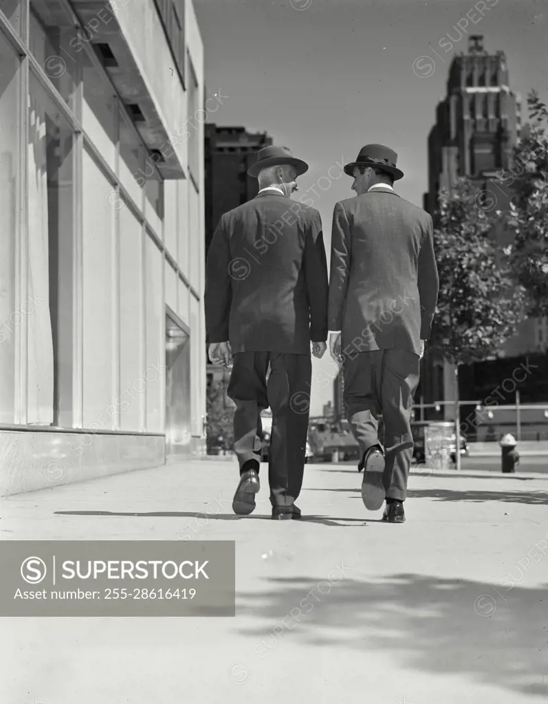 Bill Hammond, Bill Loock Models Released. Vintage Photograph. Two men wearing suits and hats walking outside on a city sidewalk away from camera