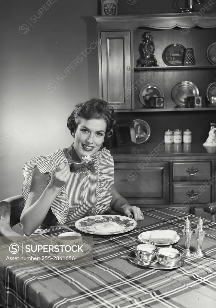 Vintage Photograph. Woman sitting at table and eating breakfast. Frame 1