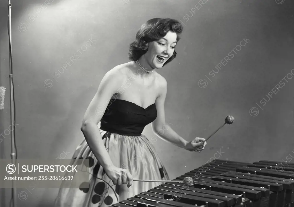 Vintage Photograph. Woman in dress and pearls playing the xylophone.